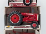 three red farmall tractors in boxes on a white surface