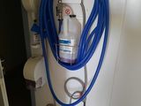 a blue hose attached to a white wall next to a toilet