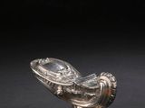 a silver plated bowl with a fish on it on a black surface