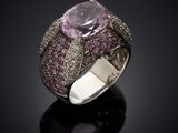 a close up of a ring with a pink stone surrounded by diamonds