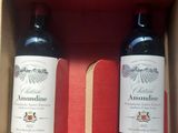 two bottles of red wine in a box on a table