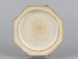 an image of a white plate with a brown rim on a metal stand
