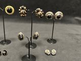 several pairs of earrings are displayed on a stand on a table