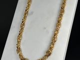 un gros plan d'un collier à chaîne en or posé sur une surface en marbre