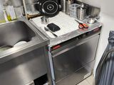 a kitchen with a sink, stove, and trash can in it