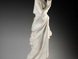 une statue en marbre blanc représentant une femme les mains jointes