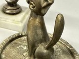 a statue of a cat sitting on a tray next to a bust of a cat