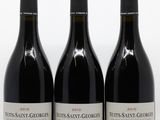 trois bouteilles de vin rouge posées sur une table blanche
