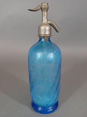 une bouteille en verre bleue munie d'une poignée en métal, posée sur une table