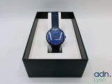 une image représentant une montre dans un coffret noir orné d'une bande bleue et blanche
