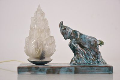 une statue d'éléphant posée sur une table, à côté d'une lampe