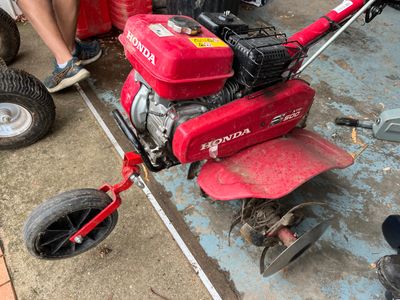 a small red lawn mower sitting on the side of the road