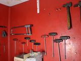 many tools hanging on a red wall in a room