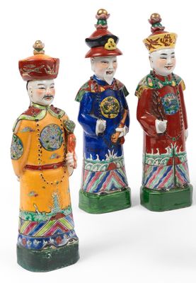 three chinese figurines of men with hats and tails on a white background