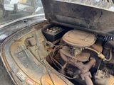an old car that has a very dirty engine in it ' s trunk
