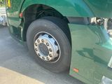 a green semi truck with a flat tire parked in a parking lot