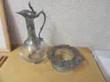 a silver pitcher sitting on a table next to a candle holder