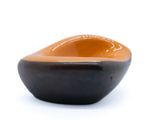 un petit bol noir et orange posé sur une surface blanche