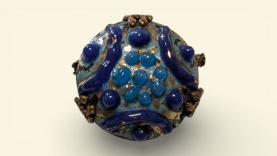 blue and gold bead on a white surface with a white background
