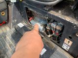 a person pointing at a car ' s engine with a wren