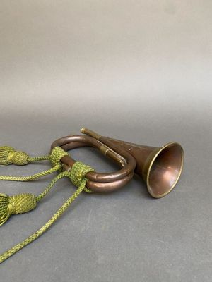 une trompette en laiton avec un cordon vert posée sur une surface grise