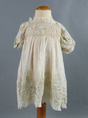 a white dress on a mannequin stand with a gray background