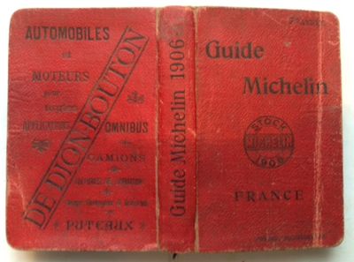 an old red book sitting on top of a table next to a white table
