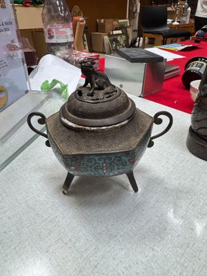 a silver teapot sitting on top of a table next to a pair of shoes