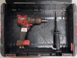 une perceuse et un marteau dans un coffret posé par terre