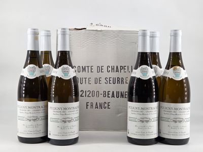 four bottles of wine are lined up in front of a silver box