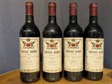 four bottles of red wine are lined up on a wooden tray