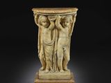 un socle en marbre surmonté de deux figures tenant un vase