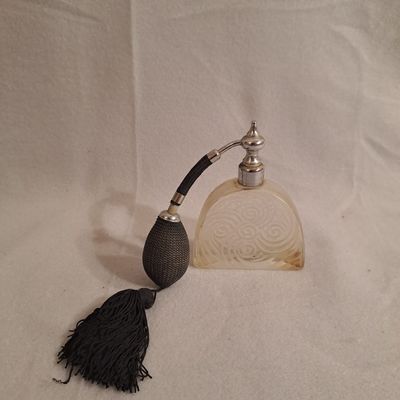 une image représentant une pipe ornée d'un pompon, à côté d'un flacon de parfum