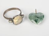 two rings and a heart shaped stone on a white surface