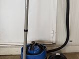 un aspirateur bleu posé sur un tapis, à côté d'un aspirateur noir