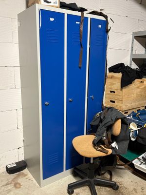 un casier bleu dans un coin de la pièce, à côté d'une chaise