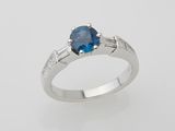 a close up of a ring with a blue stone on a white background