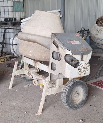 une bétonnière posée dans un garage à côté d'une brouette