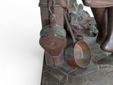 a bronze statue of a woman with pots and pans on a table
