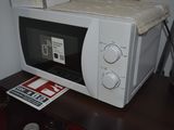 a microwave sitting on top of a table next to a lamp