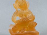 une statue en jade orange représentant un homme assis sur un rocher