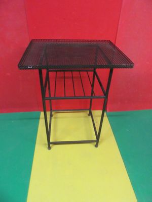 une petite table sur laquelle se trouve un panier, posée sur un sol jaune et vert