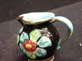 a small black vase with a flower design on it