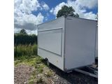 a white trailer parked on gravel near a field