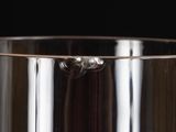 a glass vase with a silver handle on a black background