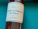 a bottle of wine sitting on a pool table with a pool cue