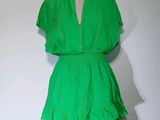 une robe verte posée sur un mannequin contre un mur blanc