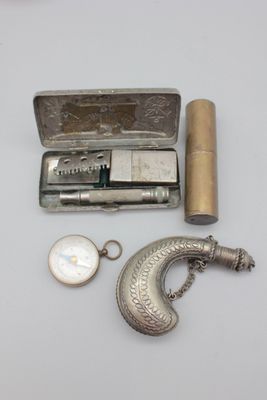 un étui en argent contenant un briquet et d'autres objets, posé sur une table