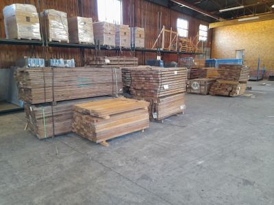 several stacks of wood sit in a warehouse with pallets on the floor