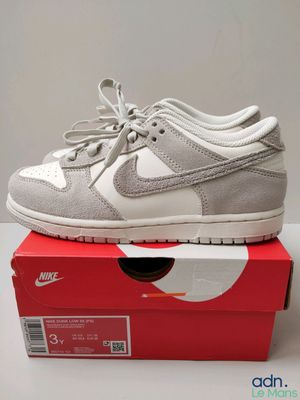 une paire de chaussures blanches et grises posée sur une boîte rouge